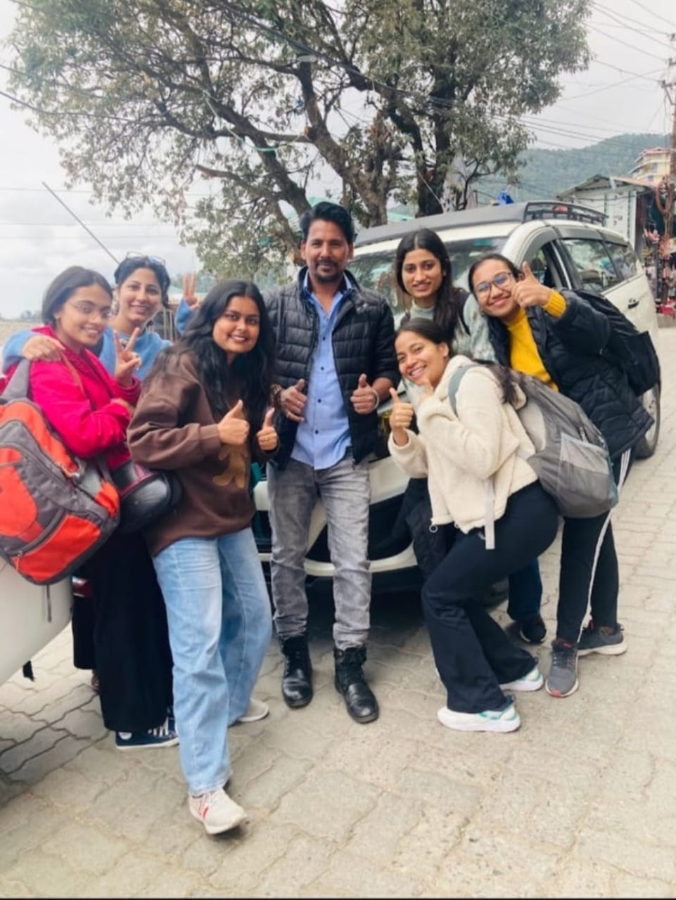Group of happy tourists posing by the car.